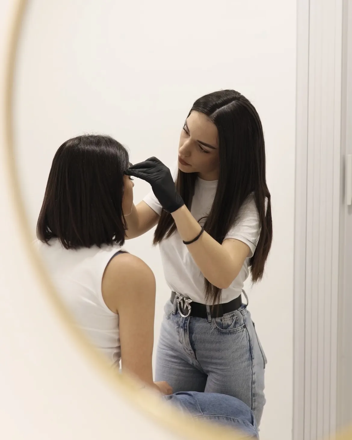 Antonella mentre disegna le sopracciglia di una cliente allo specchio